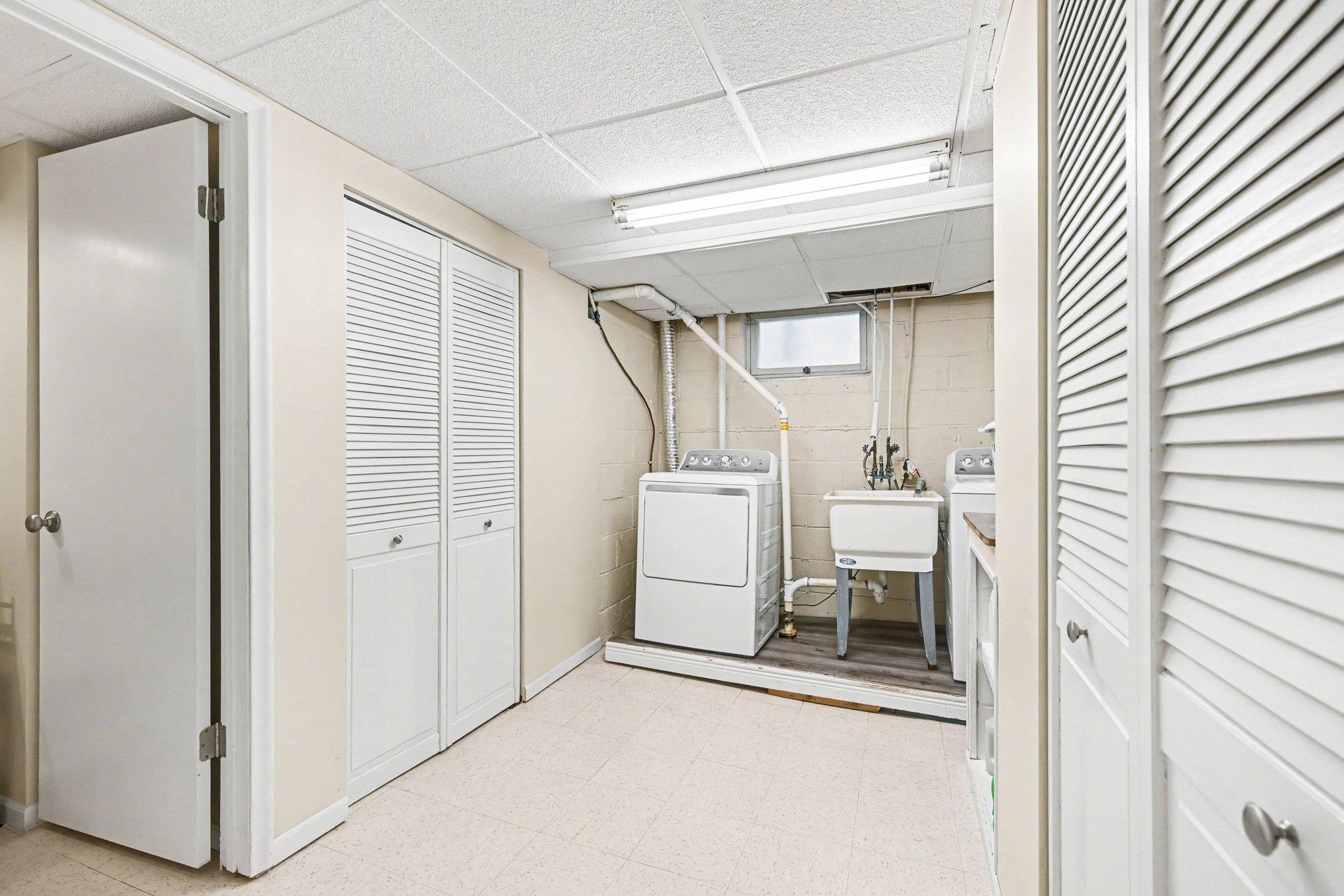 Fully finished, bright and clean laundry room with ample storage and closet space