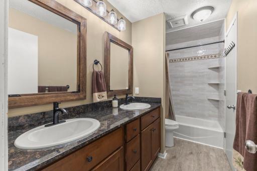 Main level full walk-through bathroom with dual sink vanity and newly tiled shower.