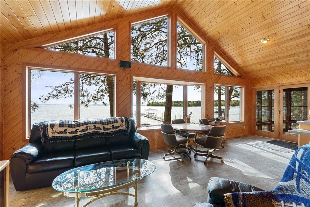 Vaulted lakeside living area with expansive windows and panoramic water views.