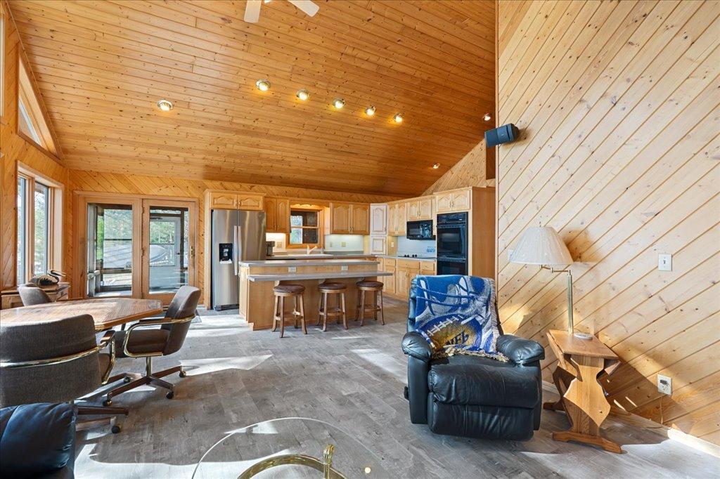 Warm knotty pine interior with open layout, breakfast bar seating, and screened porch access.