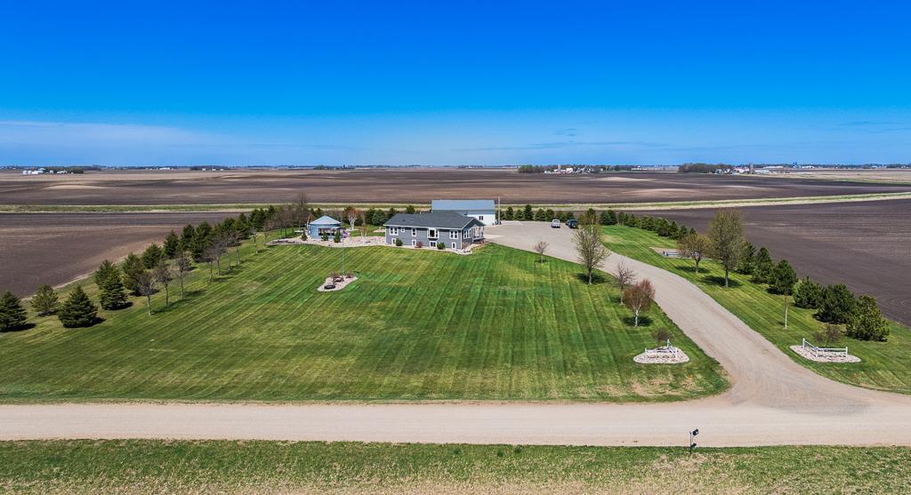 Nice wide driveway leads around to the attached garage while pine trees line the property for a clean and polished visual appeal