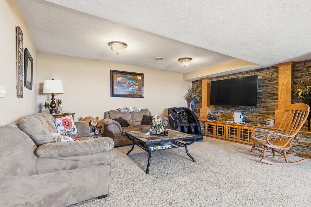 Cozy family room in the lower level boasts a stone accent wall with wooden beams