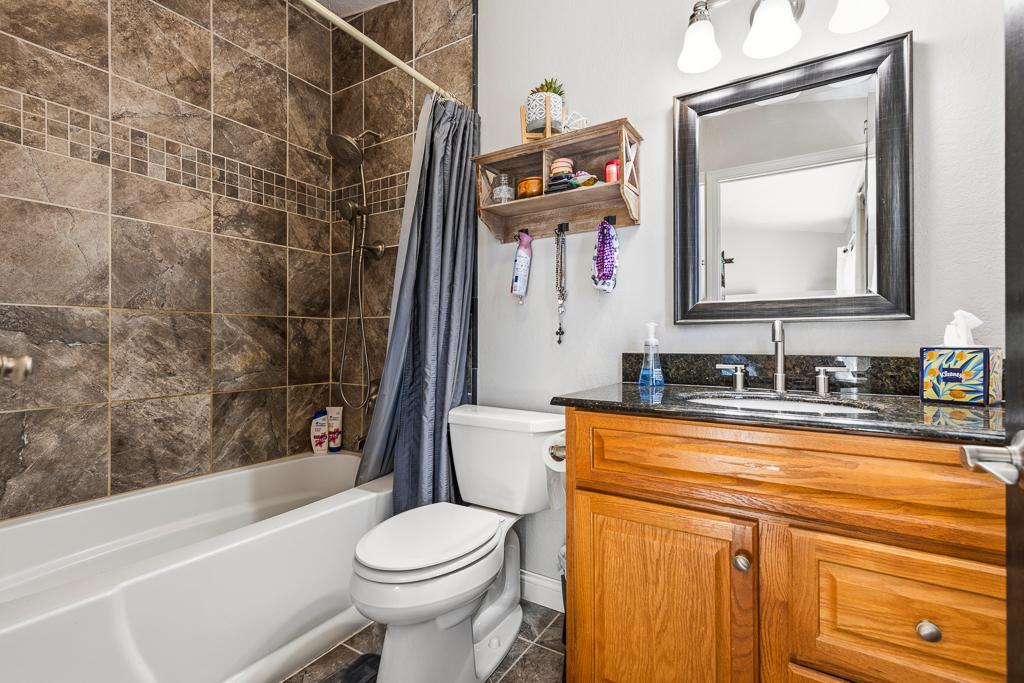 Private primary full bathroom with tiled shower and granite countertop on the vanity