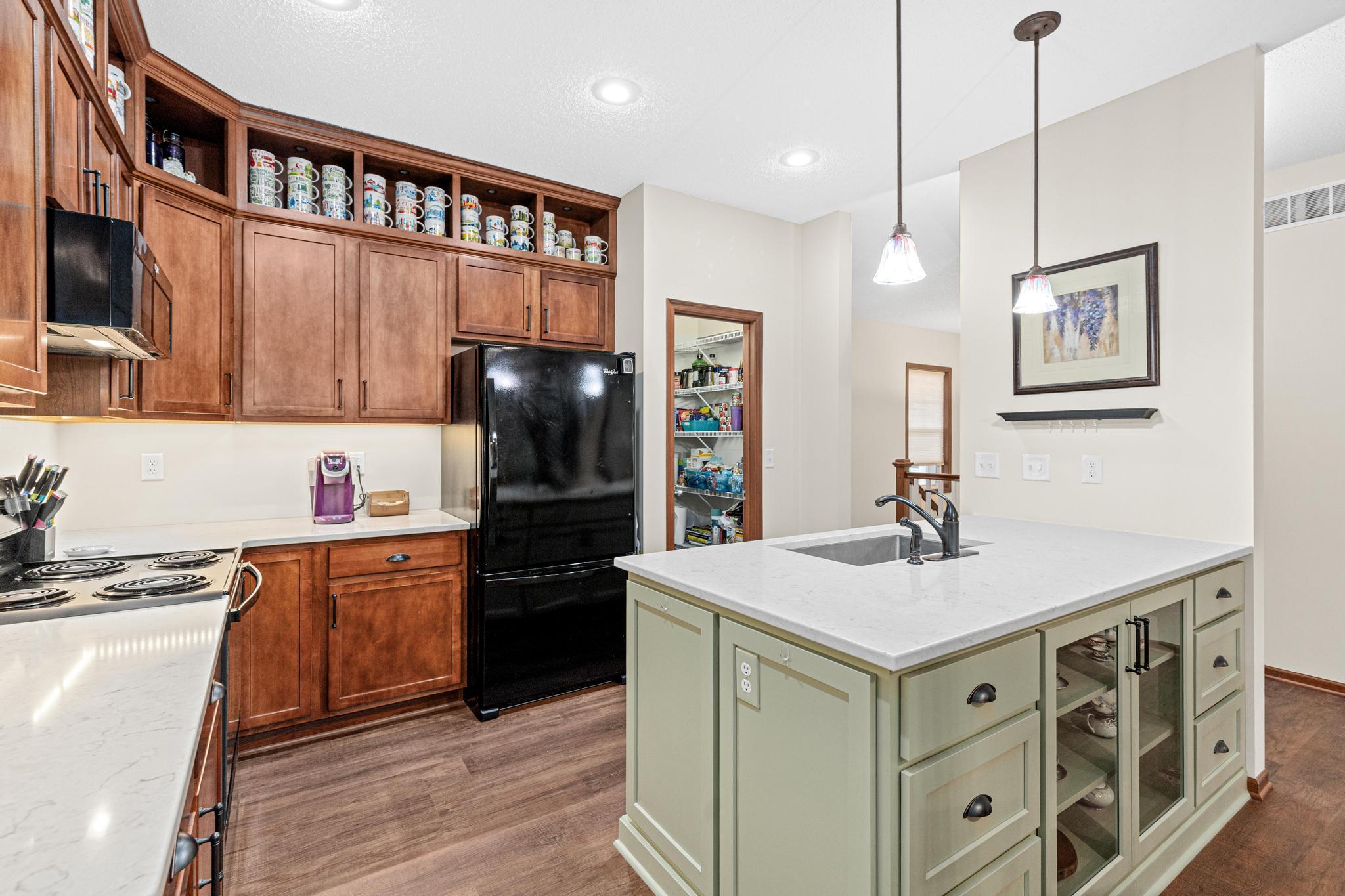 The updated kitchen features custom stone countertops, under-cabinet lighting, a center island workspace, and a walk-in pantry, making meal preparation efficient and enjoyable.