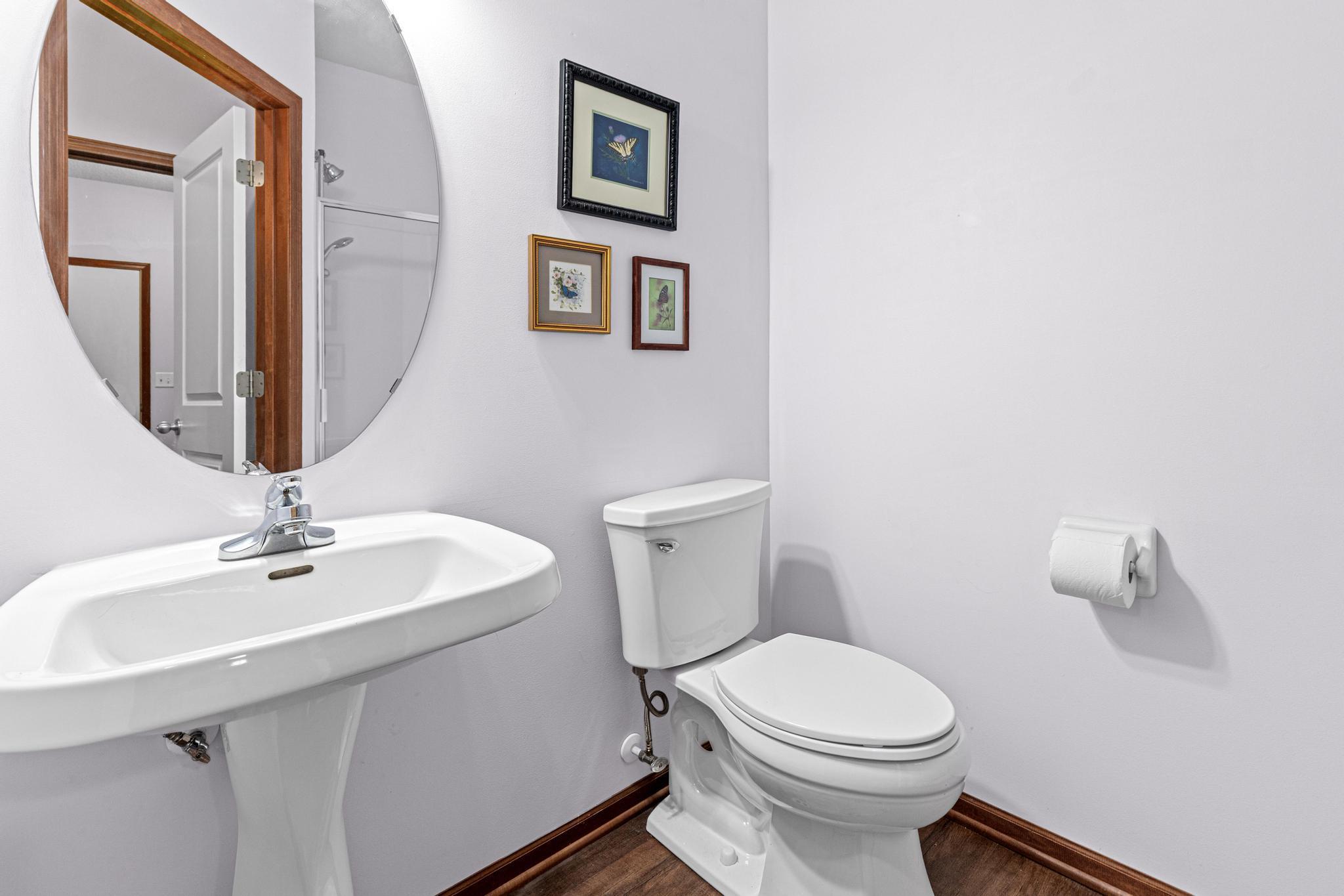 This main-floor bathroom with glass shower enclosure is located near the mudroom for comfort. A storage closet is located in the hallway for added convenience.