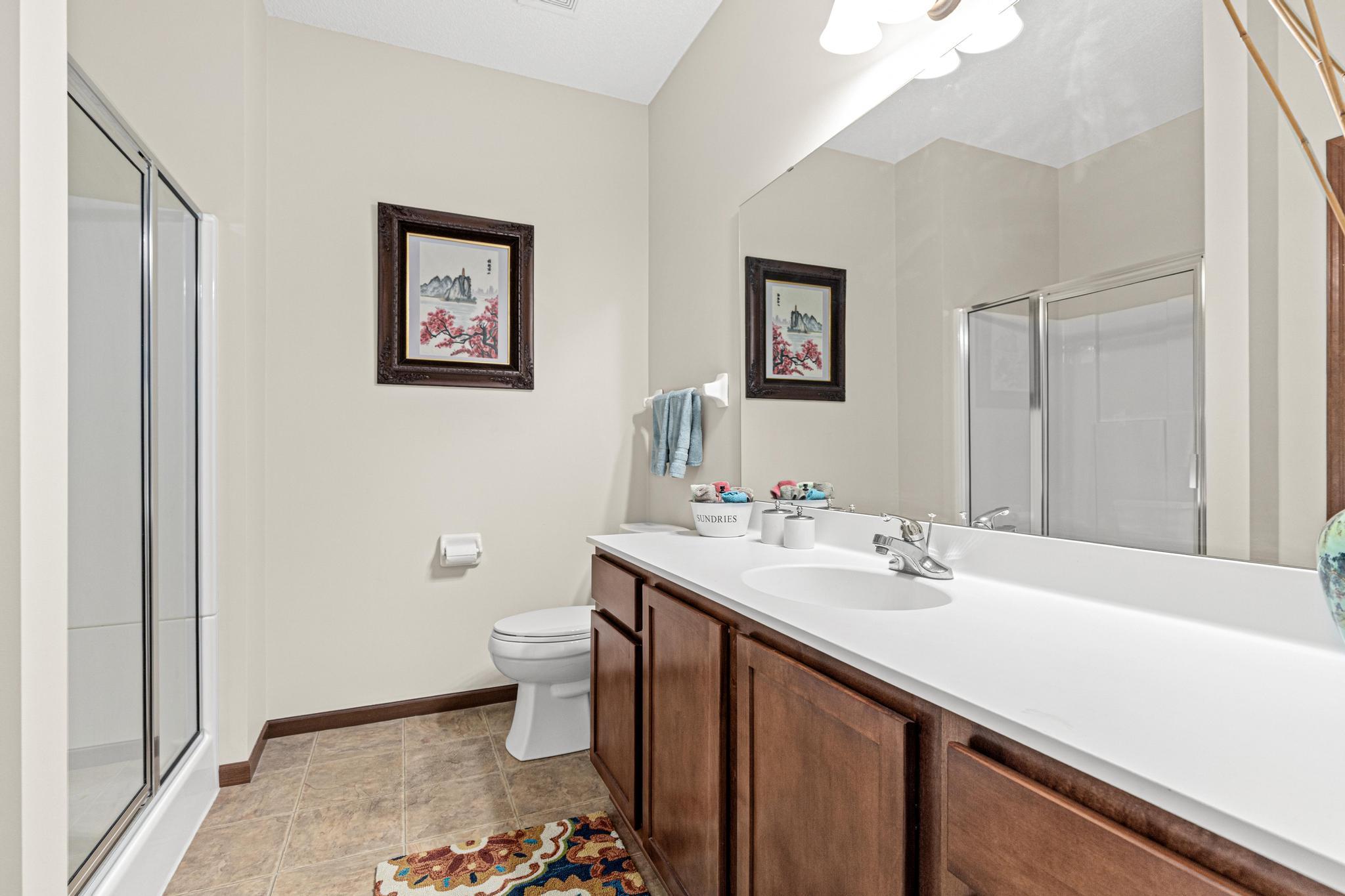 The lower level bathroom features an oversized vanity, linen storage closet and a glass shower enclosure adding to the functionality of the floor plan.
