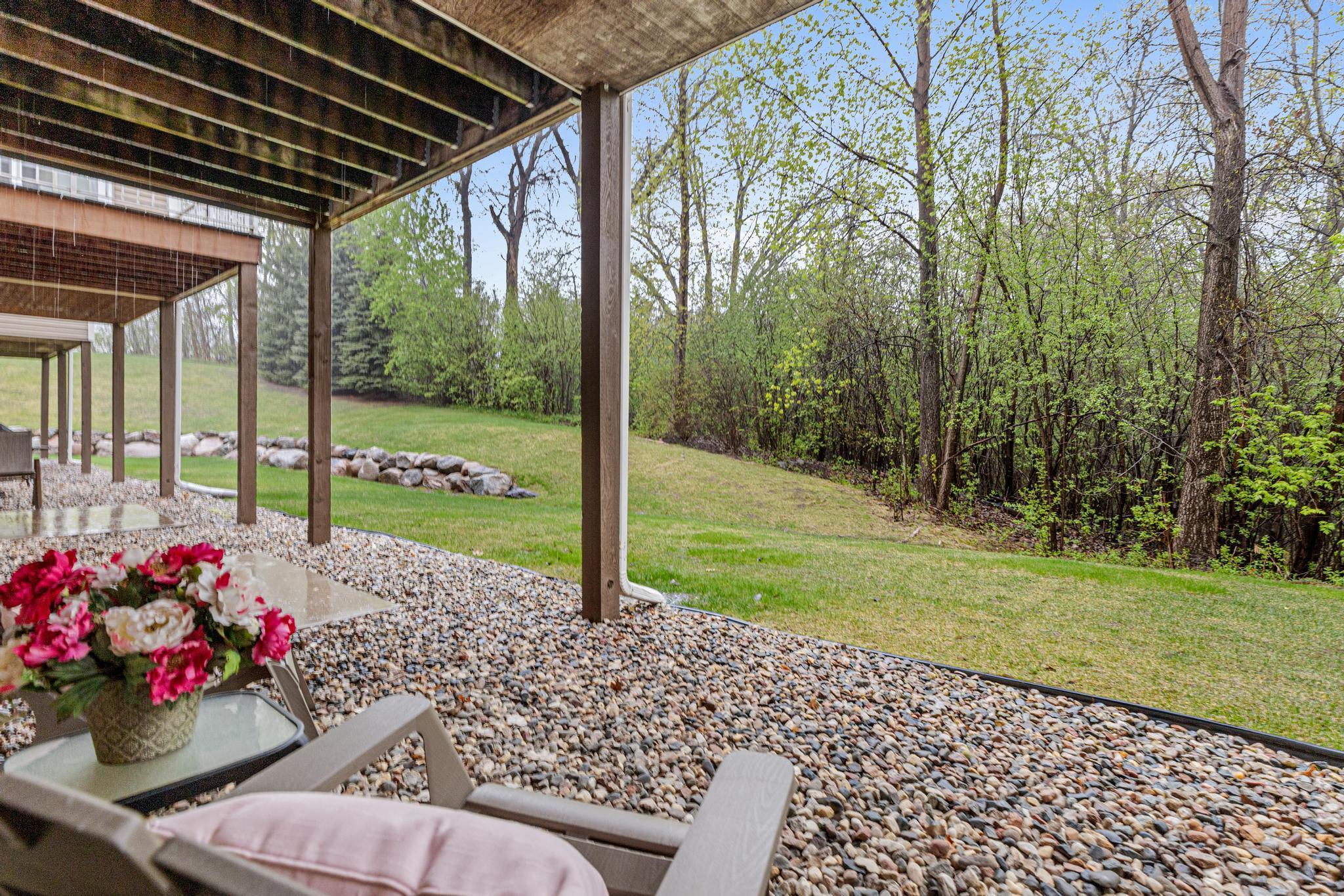 Wooded views continue from the lower level, where a concrete patio and rock area invite relaxed outdoor conversations while soaking in the spring breezes.