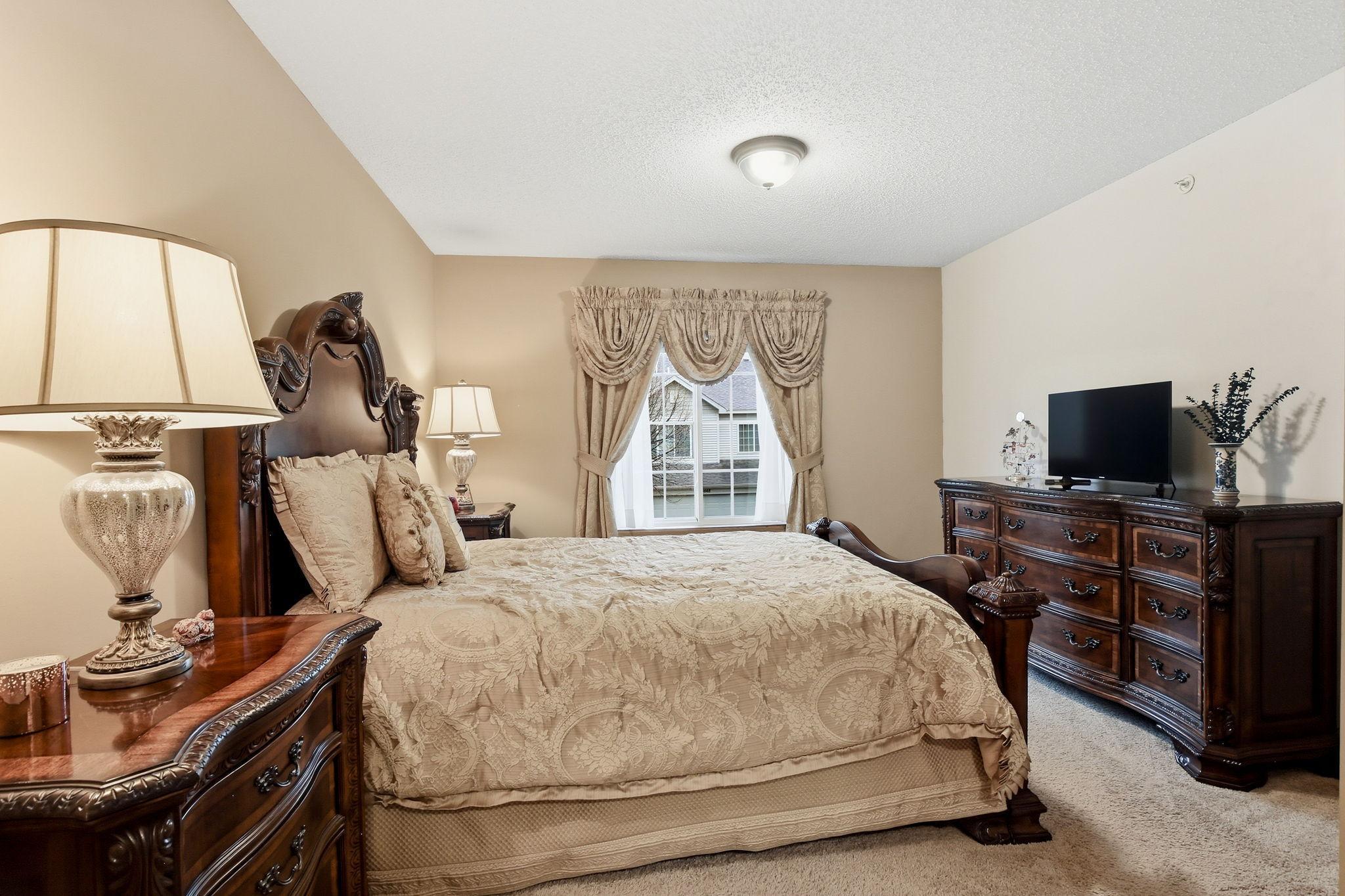 The spacious primary bedroom offers a comfortable retreat. Window coverings shown in this photo are excluded from the sale.