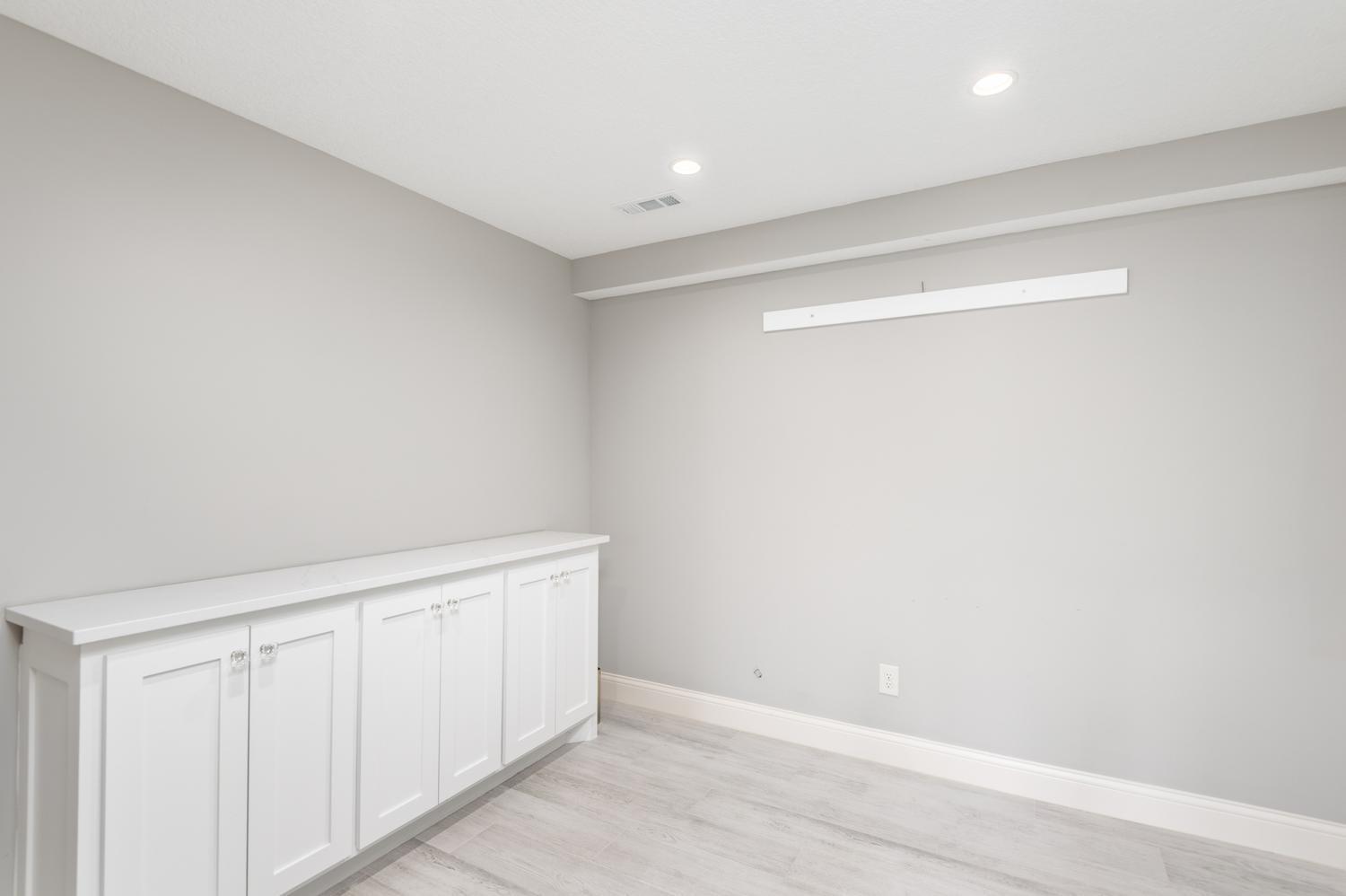 French doors step into the lower level office with heated floor, recessed lighting and built in cabinet storage.