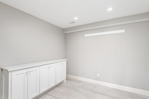 French doors step into the lower level office with heated floor, recessed lighting and built in cabinet storage.
