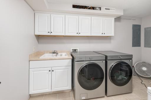 Clean and spacious laundry room with wash sink and cabinetry.