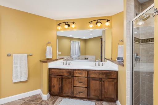 Very spacious primary bath with double vanity, tile flooring, tile shower and whirlpool tub.