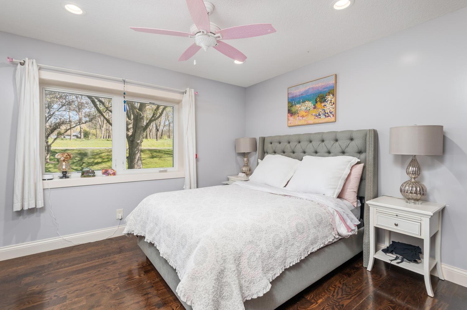 The third bedroom on the main floor. Beautiful wood plank floors, recessed lighting and pink ceiling fan.