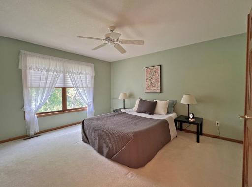 Spacious bedroom featuring neutral carpeting, a ceiling fan, and a large window with backyard views.