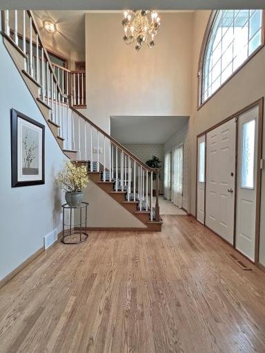 Dramatic two-story foyer featuring an arched window, hardwood floors