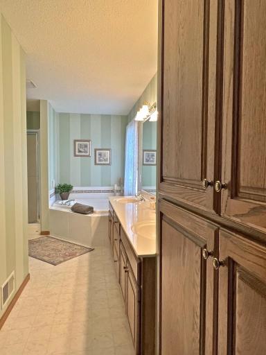 Bathroom view highlighting the large vanity, built in cabinetry, soaking tub & walk in shower