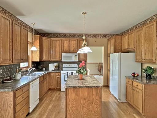 Spacious kitchen featuring extensive wood cabinetry, generous counter space, hardwood floors, and an open layout