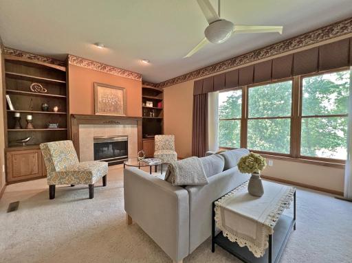 Bright family room with a fireplace, built-in storage, expansive windows, and comfortable gathering space