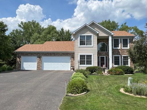 Impressive two-story exterior featuring a three-car garage, manicured landscaping, and a welcoming covered entry