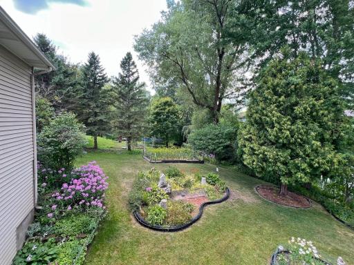 Professionally landscaped backyard featuring curved garden beds, mature trees, and a peaceful natural setting