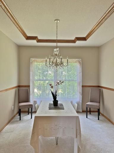 Formal dining room featuring elegant trim, a statement chandelier, and a large window overlooking the yard