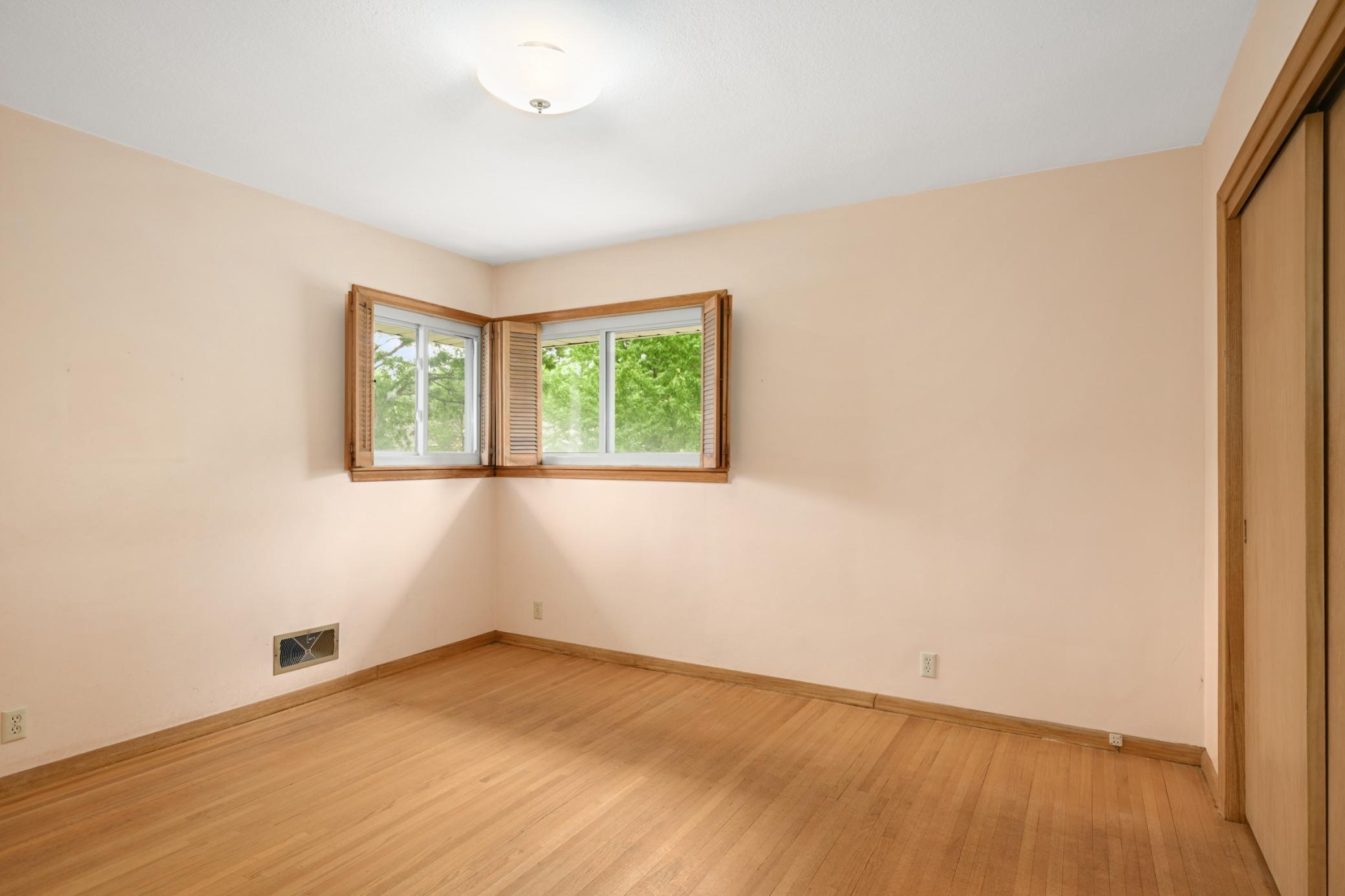 1st bedroom (11' x 12') with corner windows and original hardwood floor.