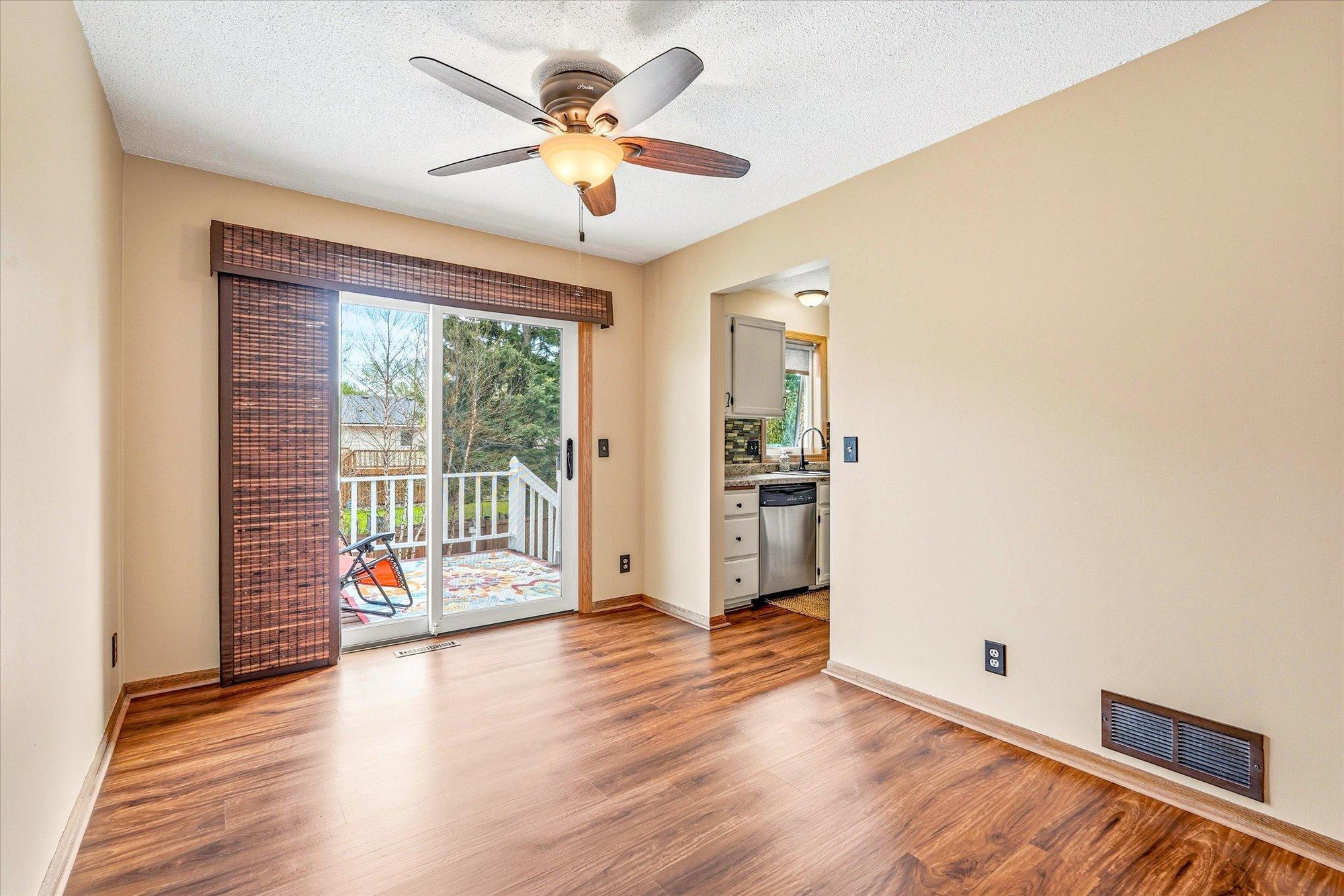 Bright dining space featuring updated flooring and convenient access to both the kitchen and deck.