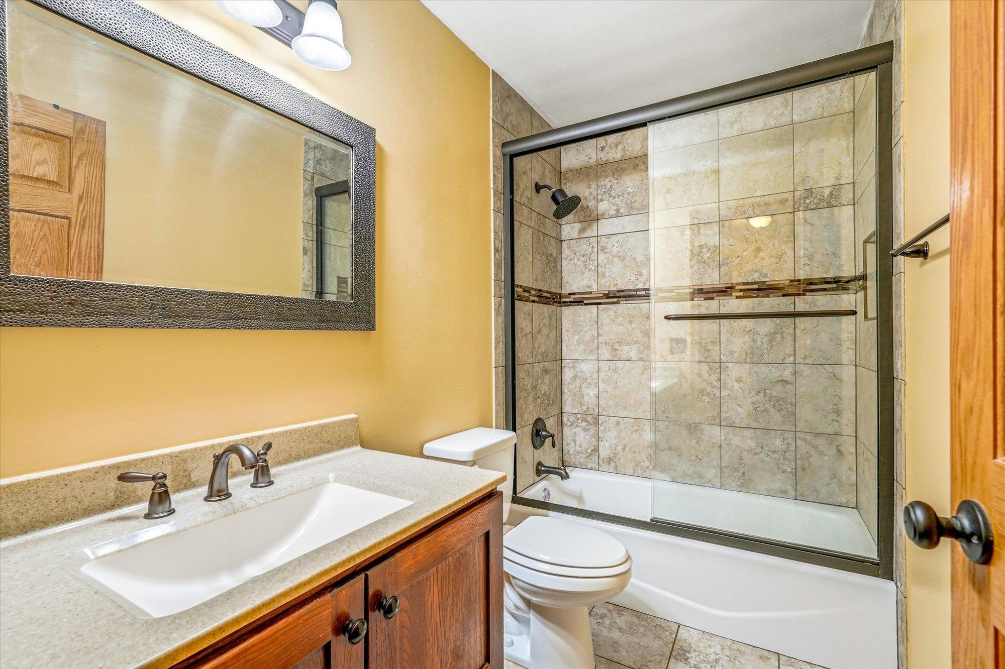 Beautifully updated full bathroom with tiled surround, updated vanity, and modern finishes.