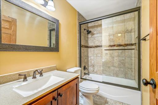 Beautifully updated full bathroom with tiled surround, updated vanity, and modern finishes.