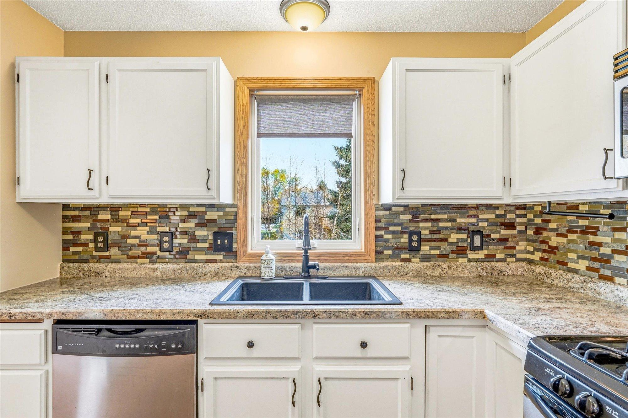 Kitchen details include updated countertops, stylish backsplash accents, and a window overlooking the backyard.