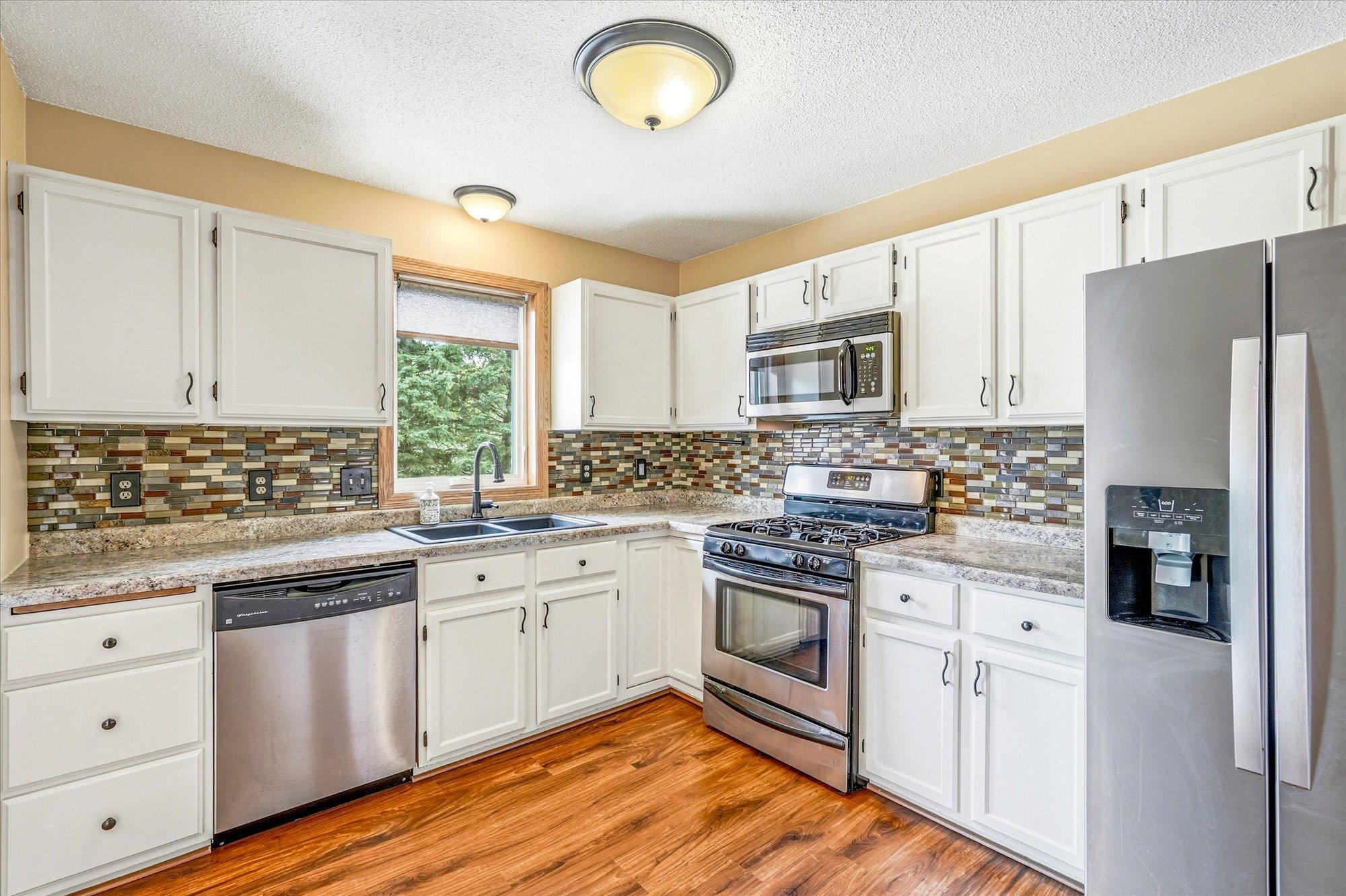 The kitchen offers updated countertops, stylish backsplash details, and a bright window overlooking the backyard.