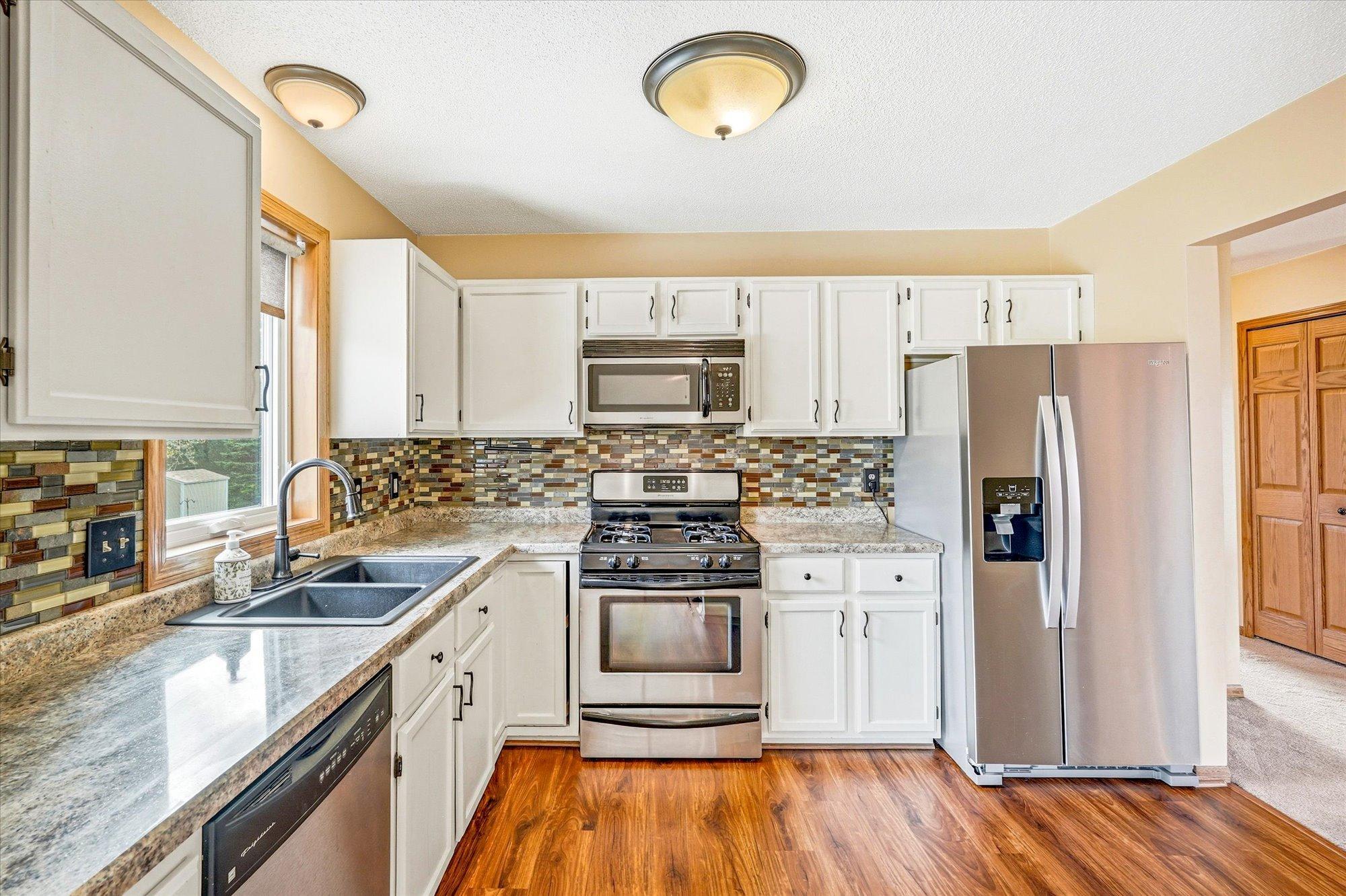 Updated kitchen with stainless steel appliances, attractive tile backsplash, and ample cabinet and counter space.