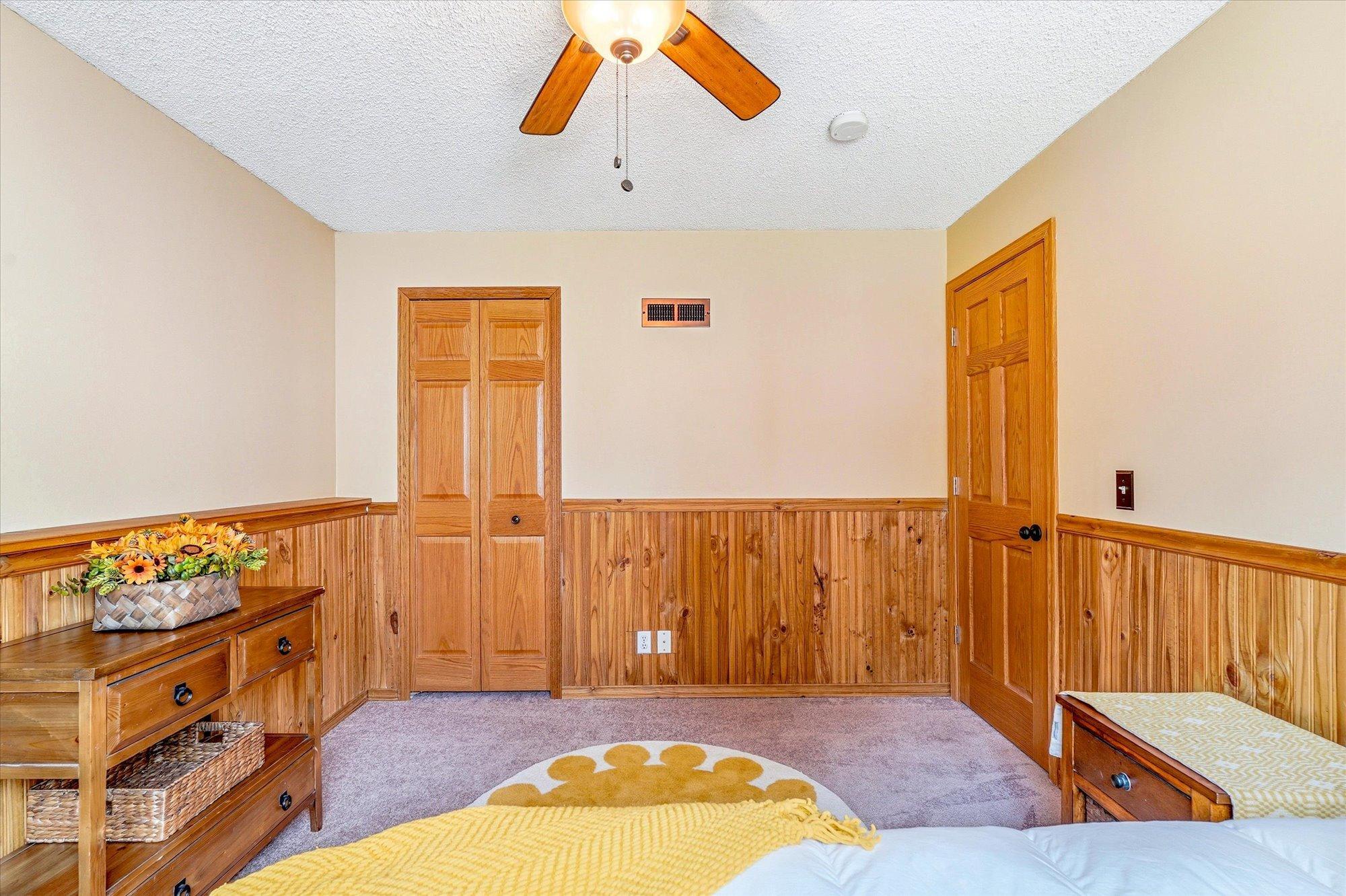 Lower-level bedroom includes ample closet space, solid wood doors, and charming wood detail throughout.