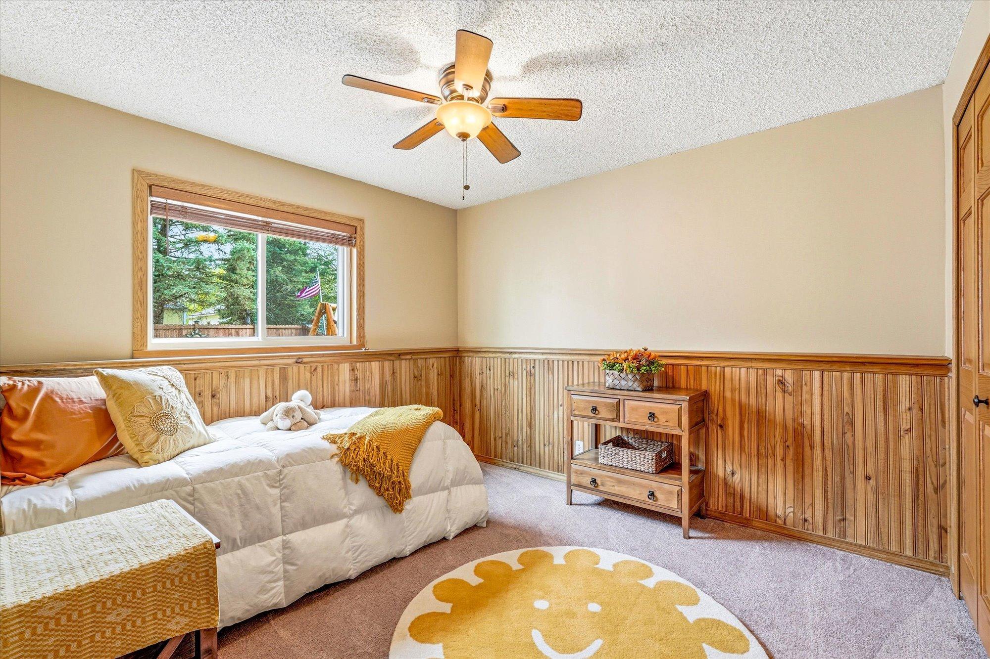 Comfortable lower-level bedroom featuring warm wood accents, natural light, and neutral finishes.