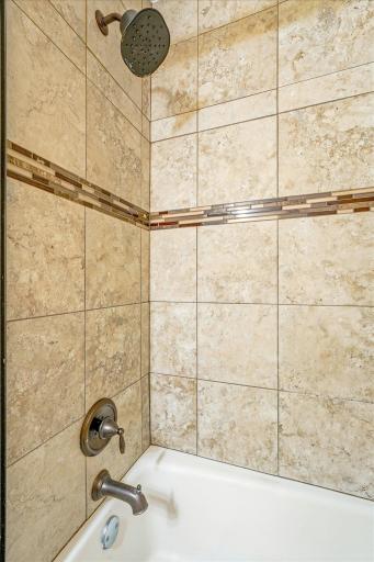 The updated bathroom features elegant tilework and a sleek glass shower door.