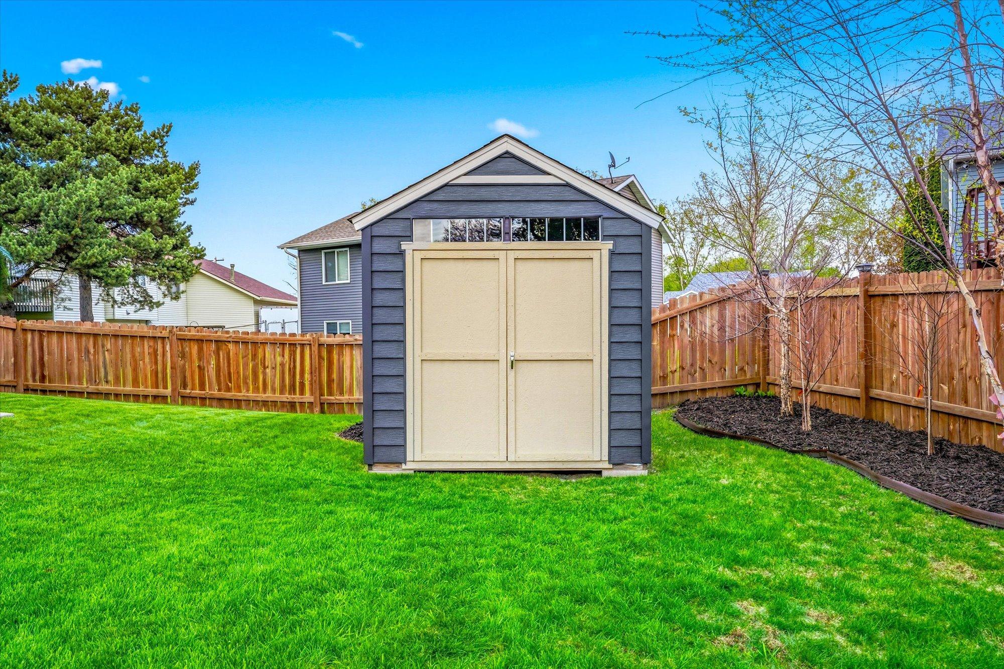 Storage shed provides excellent space for lawn equipment, tools, and additional outdoor storage.