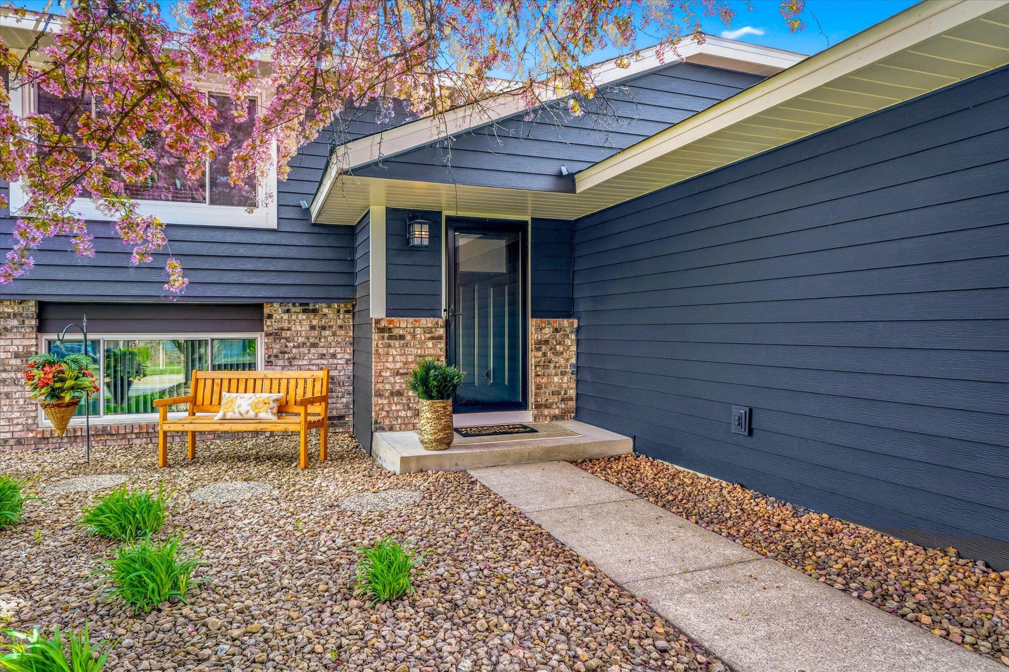 Welcoming front entry with updated exterior finishes, attractive landscaping, and covered front porch area.