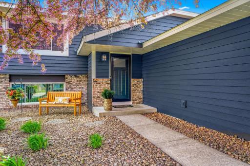 Welcoming front entry with updated exterior finishes, attractive landscaping, and covered front porch area.