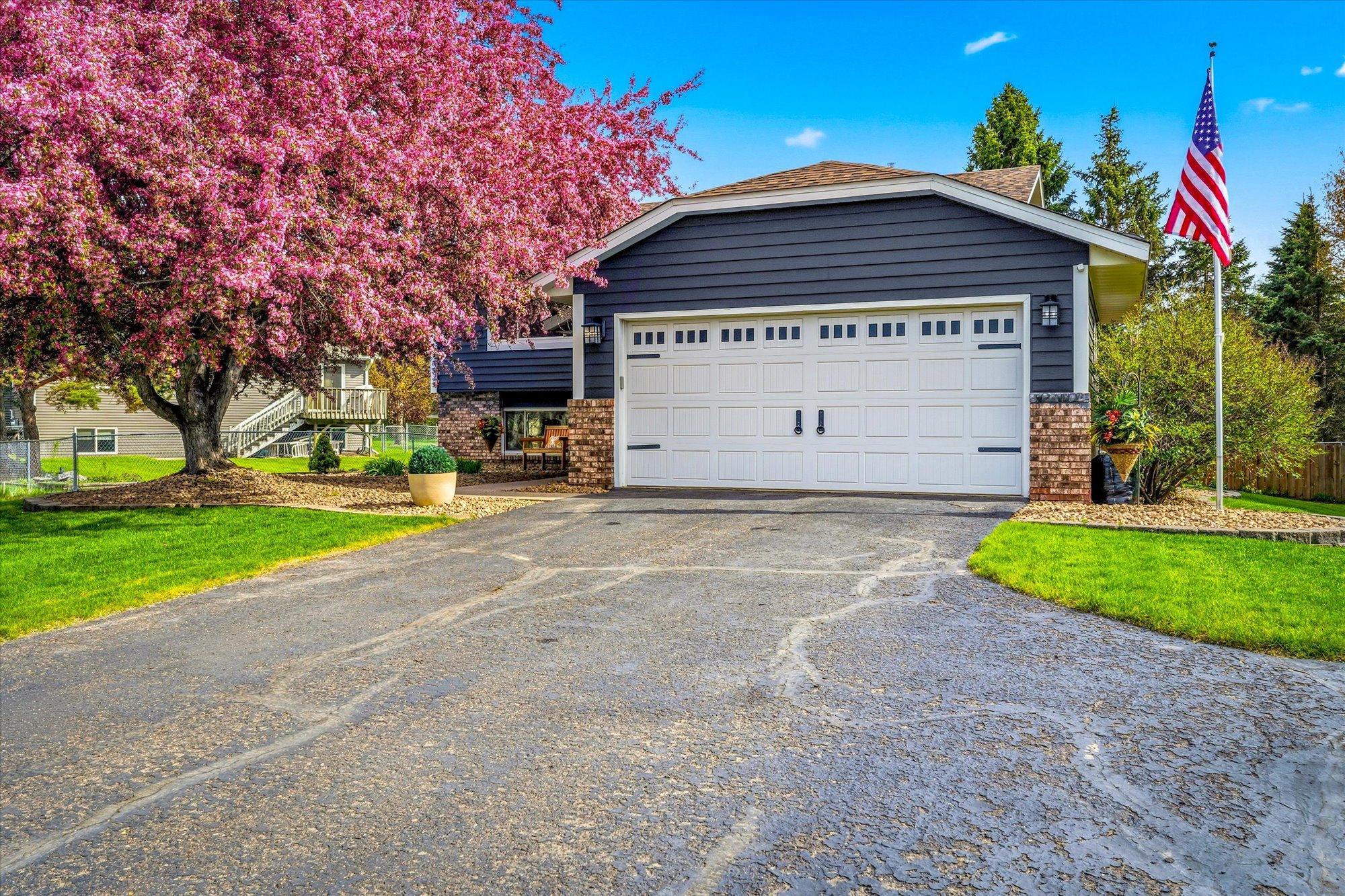 Well-maintained split-level home featuring updated metal siding, attractive landscaping, and a spacious driveway leading to the heated insulated garage.