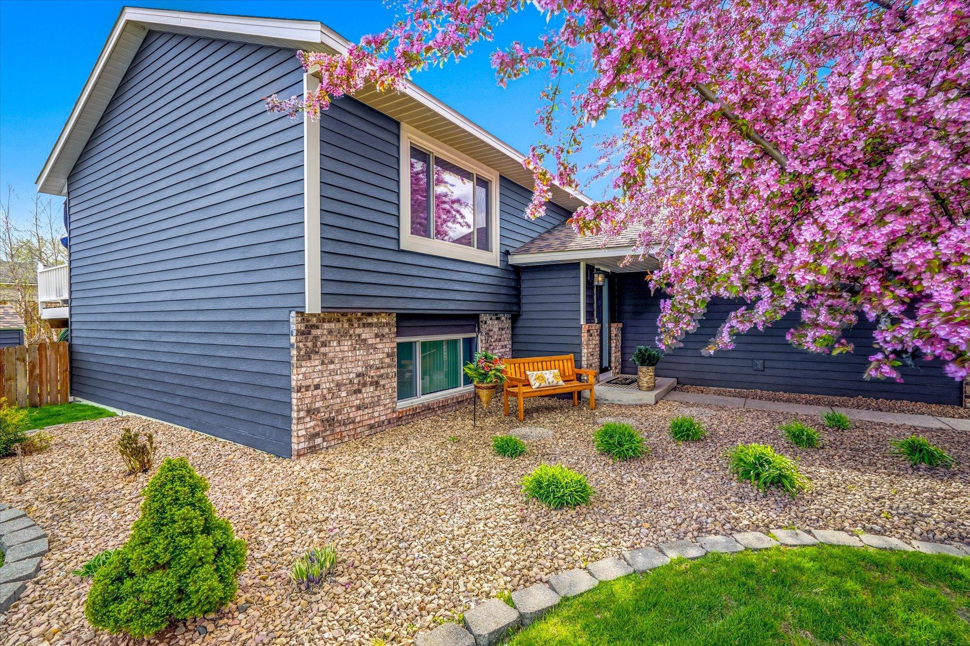 Another angle of the front exterior highlighting the attractive landscaping, newer metal siding, and charming entryway.