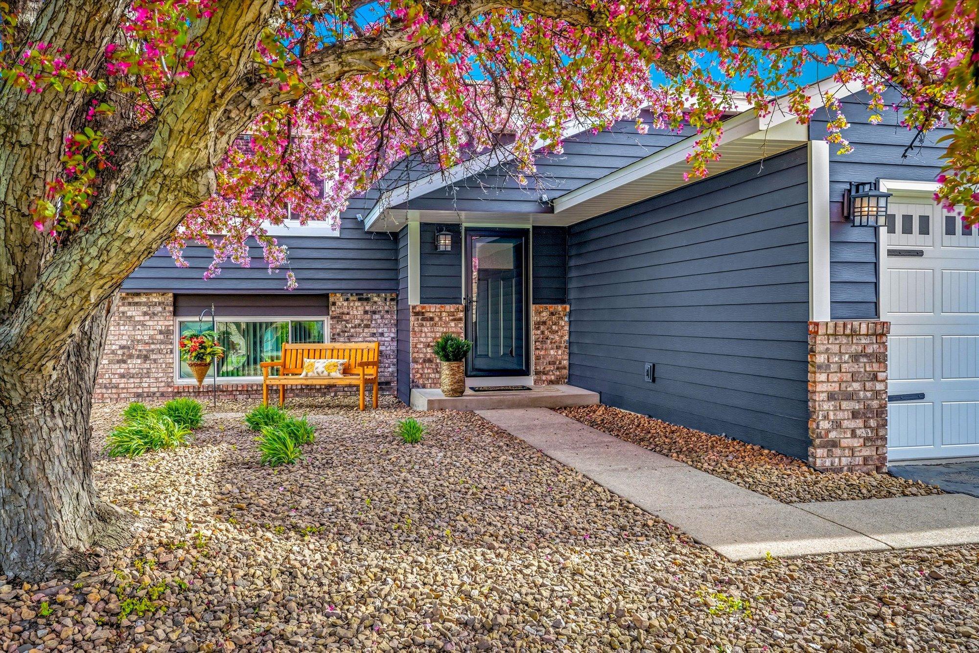 Inviting front entry with covered porch area, beautiful landscaping, and updated exterior finishes.