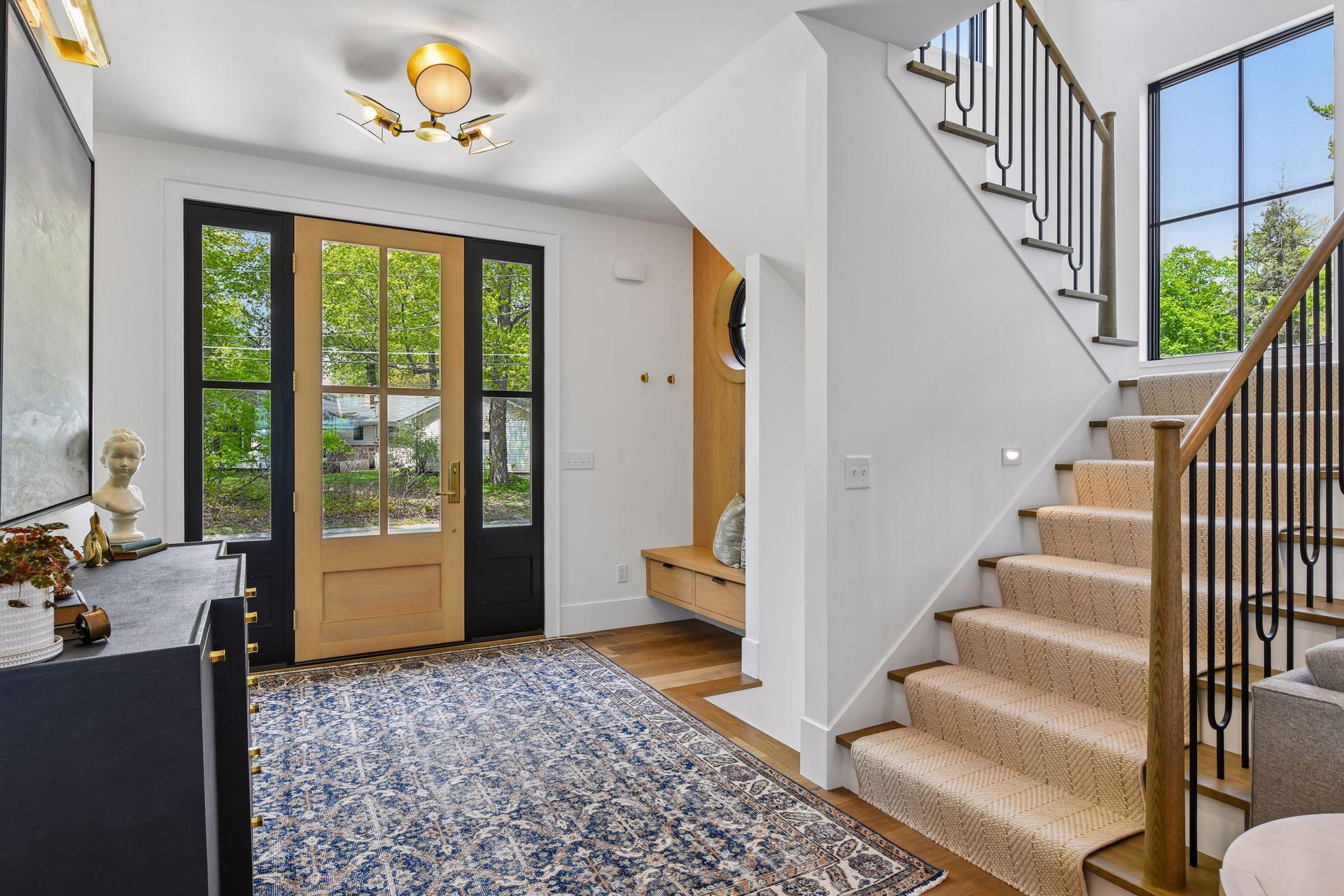 Expansive foyer with storage bench and a cute window offering a nautical touch to the lake home. Patterned wool carpet runner on the stairs.