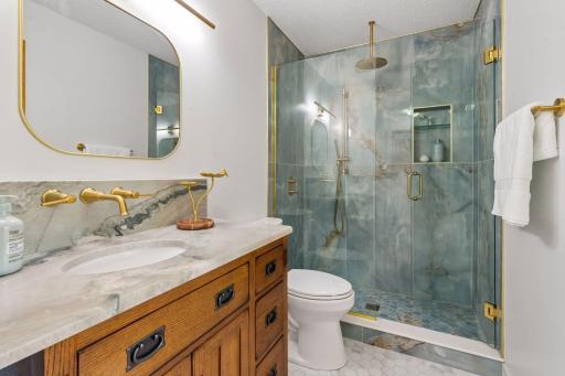 Newly remodeled bathroom on the main level, includes a step-in shower with dual shower head and glass doors.