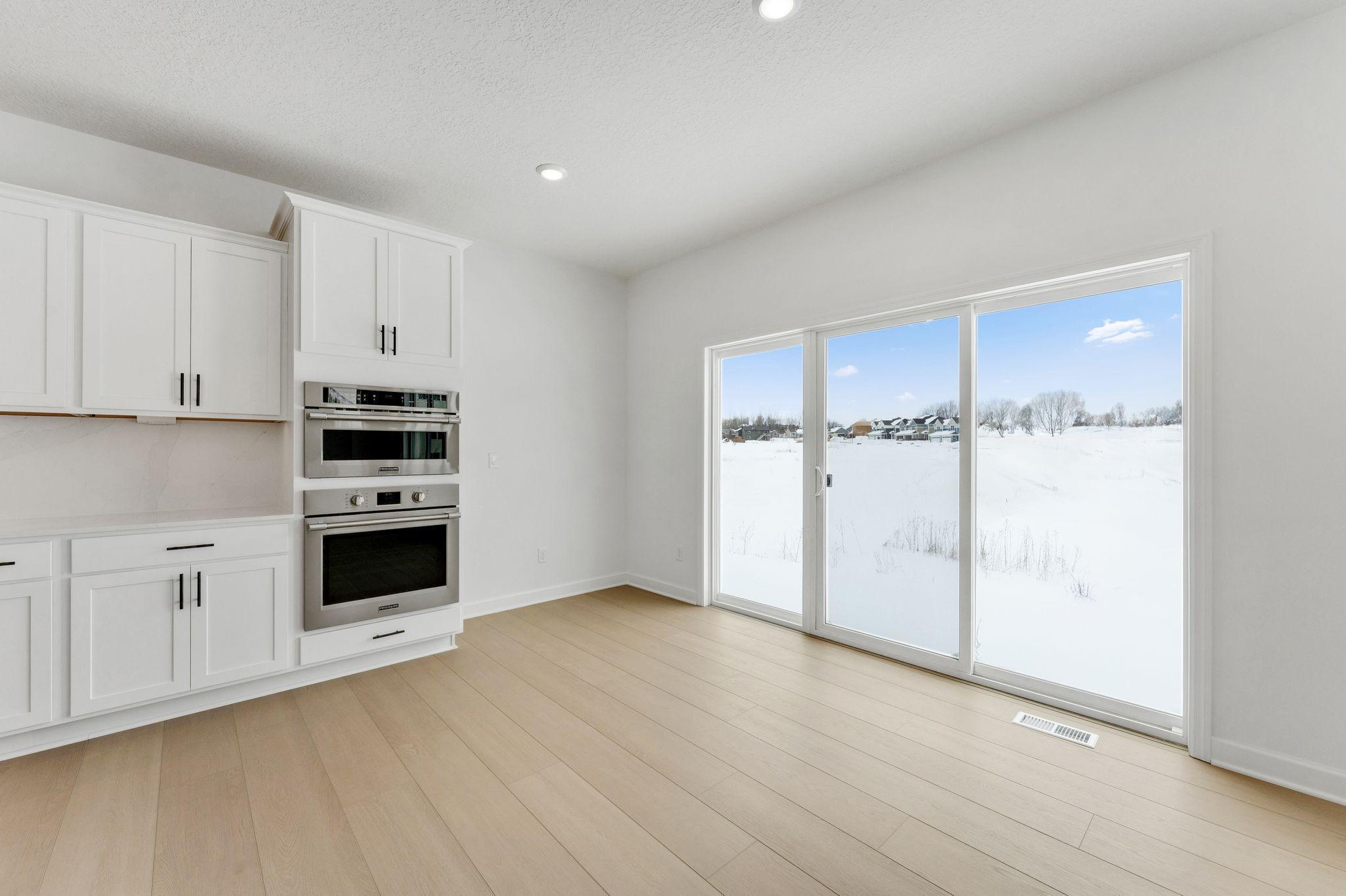 (Photo of a similar home, actual finishes may vary) Situated in front of large glass-sliders, this dining room is washed in natural light and provides a place to serve piping-hot meals straight out of the oven.