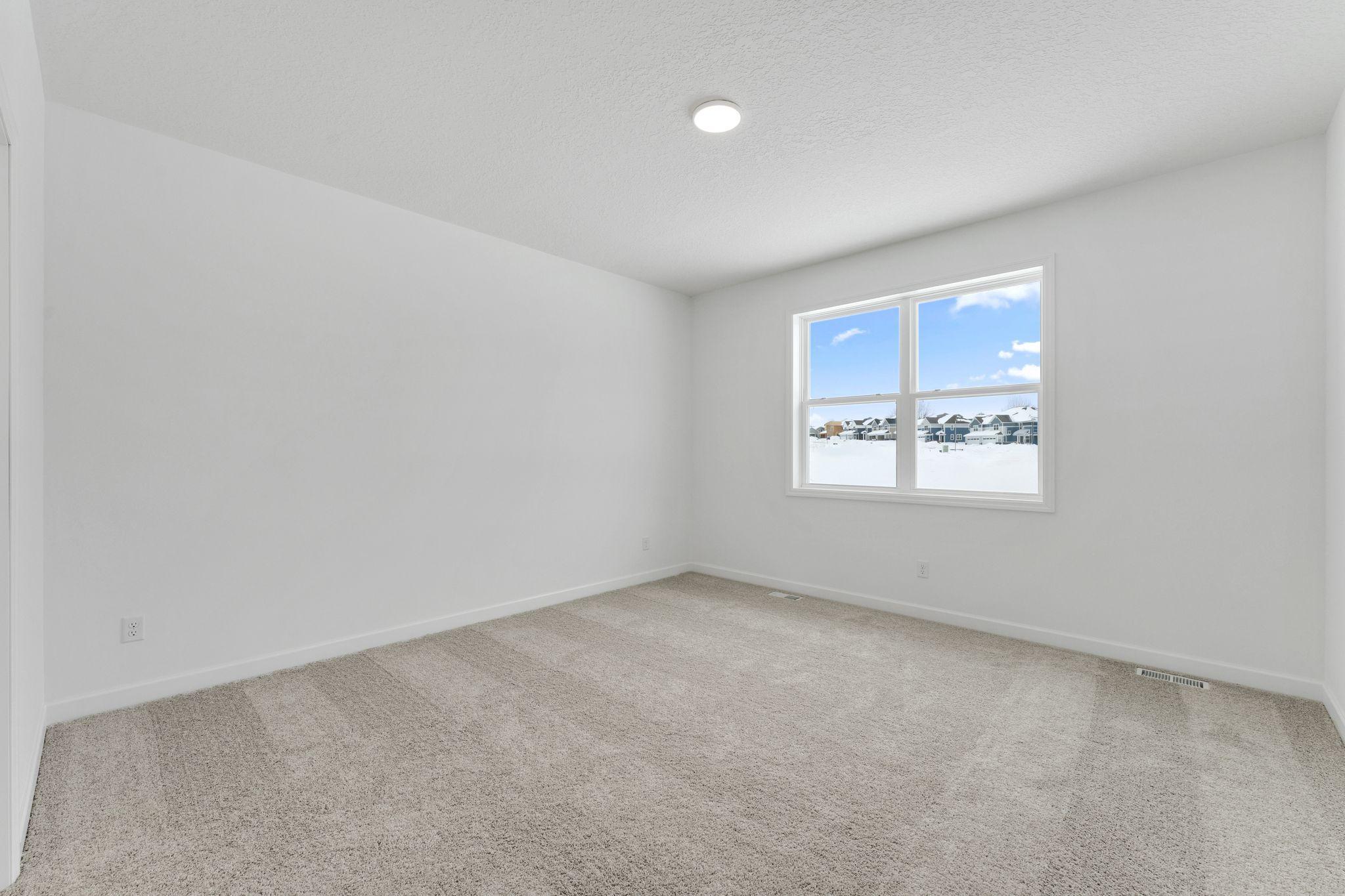 (Photo of a similar home, actual finishes may vary) The owner’s suite is a restful retreat tucked away at the back of the home, complete with a spacious walk-in closet and a well-equipped bathroom designed for shared living.