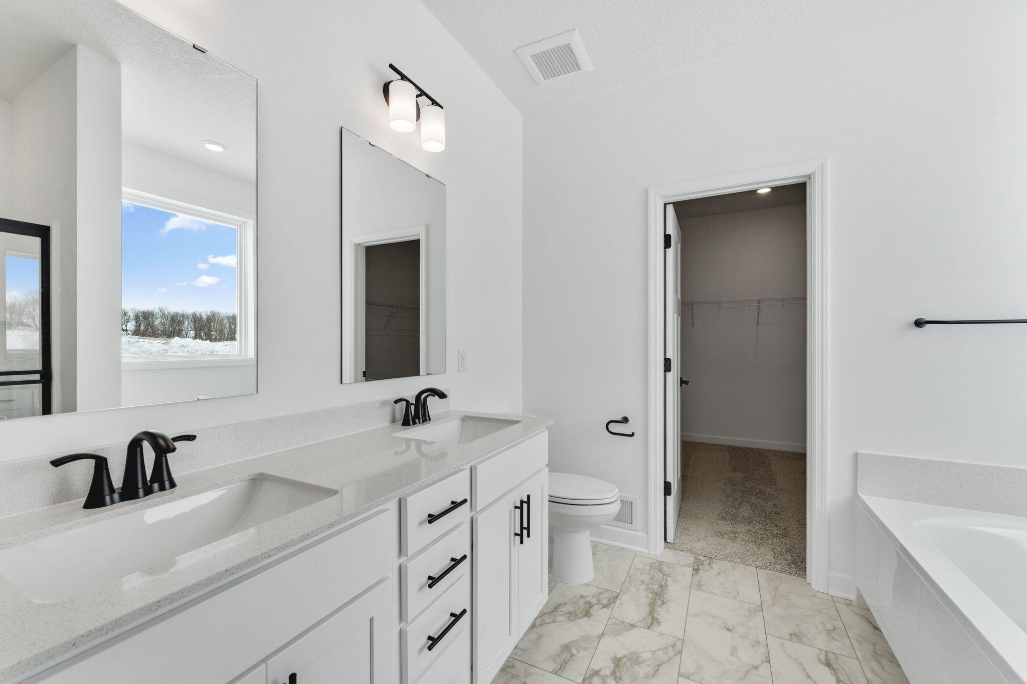 (Photo of a similar home, actual finishes may vary) Designed for utmost versatility, the en-suite bathroom features a glass-enclosed shower for daily cleaning rituals and a corner tub perfect for indulgent soaks