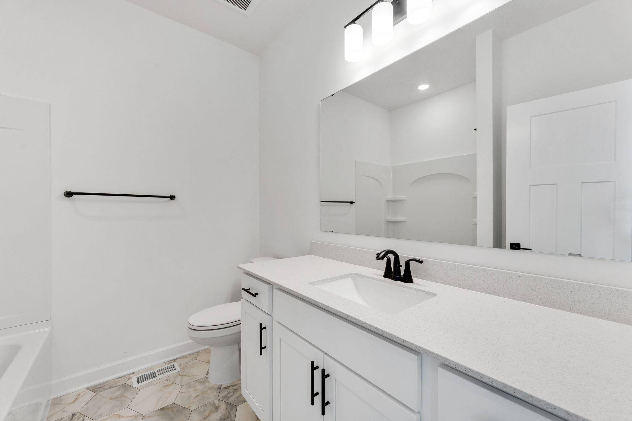 (Photo of a similar home, actual finishes may vary) Situated just off the foyer, this full bathroom is easily accessed from each of the main-floor secondary bedrooms for family members or guests.