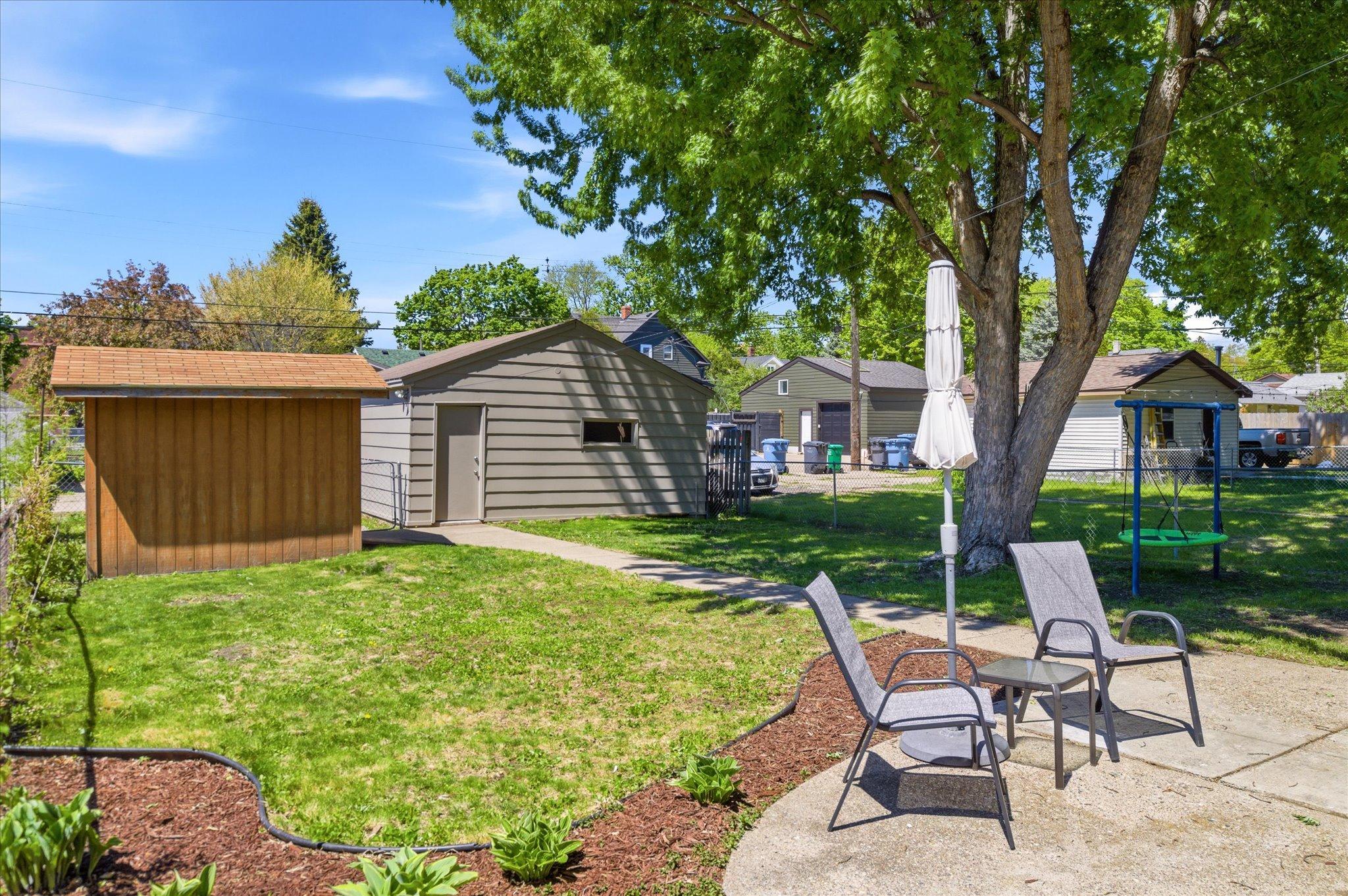 The backyard offers convenient access to both the garage and storage shed while providing functional outdoor space to enjoy.