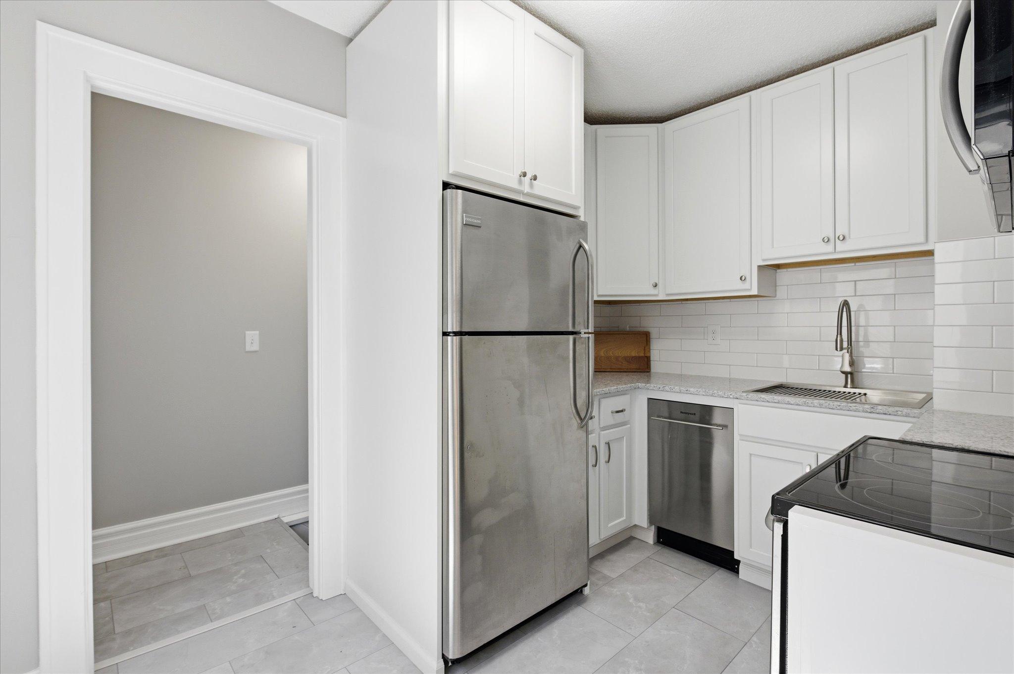 The remodeled kitchen shines with a bright, clean design featuring tiled floors, crisp cabinetry, and a welcoming atmosphere.