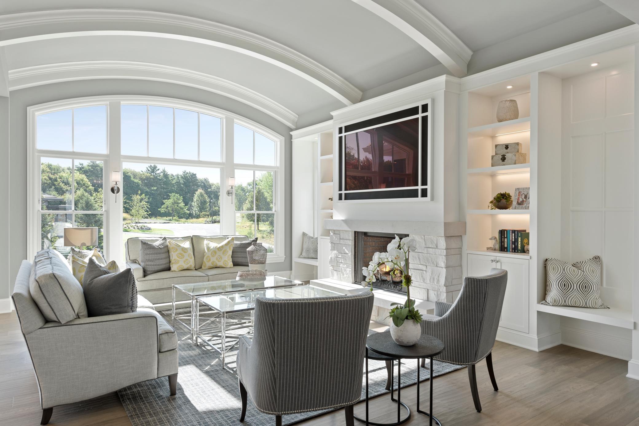 Sun-drenched Great Room with soaring ceilings, elegant millwork, and a statement arched window overlooking serene views